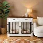 OnePaw ELARA white pet crate with black bars in a living room setting with a couch, lamp, and plant.