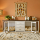 OnePaw ATHENA pet crate with bed inside, white console table with decorative items, and floral tapestry on peach wall.