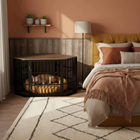 OnePaw EIRENE dog sleeping in a black wire crate in a bedroom with a bed and decor.