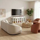 Modern living room with a white sofa, brown armchair, and white pet crate.