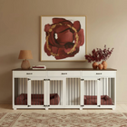 White pet crate with maroon cushioned beds inside, placed on a wooden console table against a beige wall with abstract art.