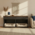 Living room with a wooden console table featuring pet beds underneath, decorative items on top, and a wall hanging.