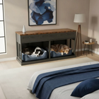 Two dogs in pet crates inside a wooden console table in a bedroom.