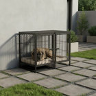 Dog lying inside a large metal dog crate on a patio with a garden background