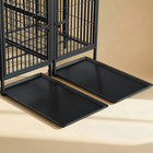 Two black pet cage mats in front of a metal pet cage on a beige surface.