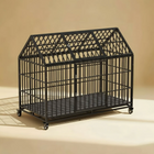 Large black metal pet cage on a beige background