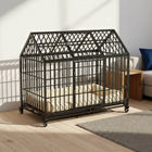 Large black metal pet cage with a cushioned interior in a room with a couch and rug.