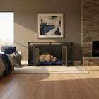 Dog lying on a blue bed inside a modern living room with a fireplace and abstract art.