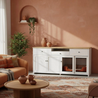 Living room with a white pet crate, orange sofa, and decorative items against a pink wall.